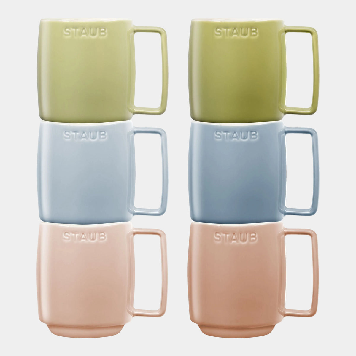 Set of four Staub mugs in green, blue, pink, and beige on a white background