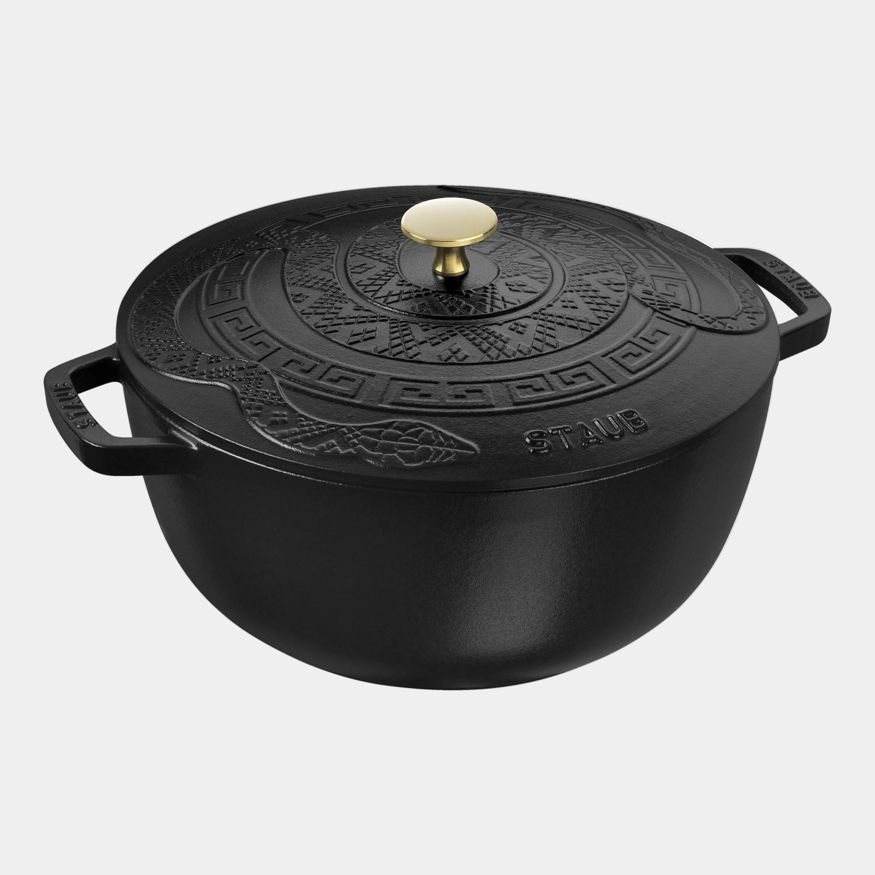 Black cast iron pot with decorative lid on a white background
