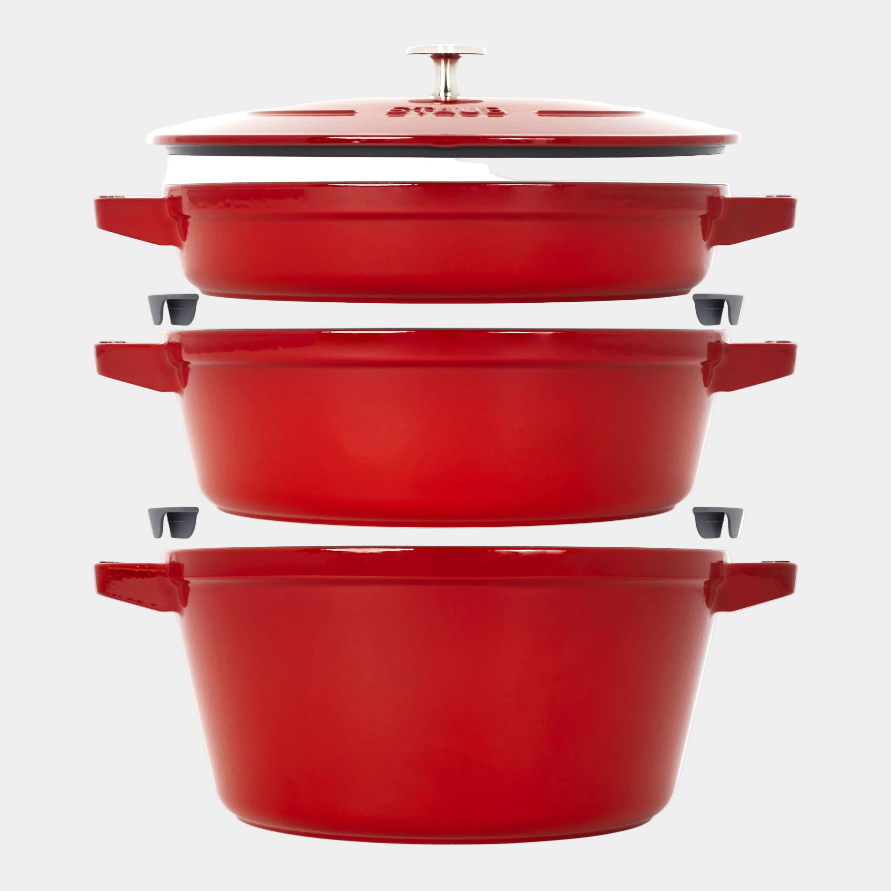 Set of red enameled cast iron cookware on a white background