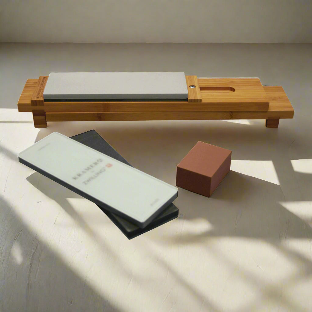 ZWILLING Sharpening Stone Set with bamboo sink bridge and various grit sharpening stones on a table.