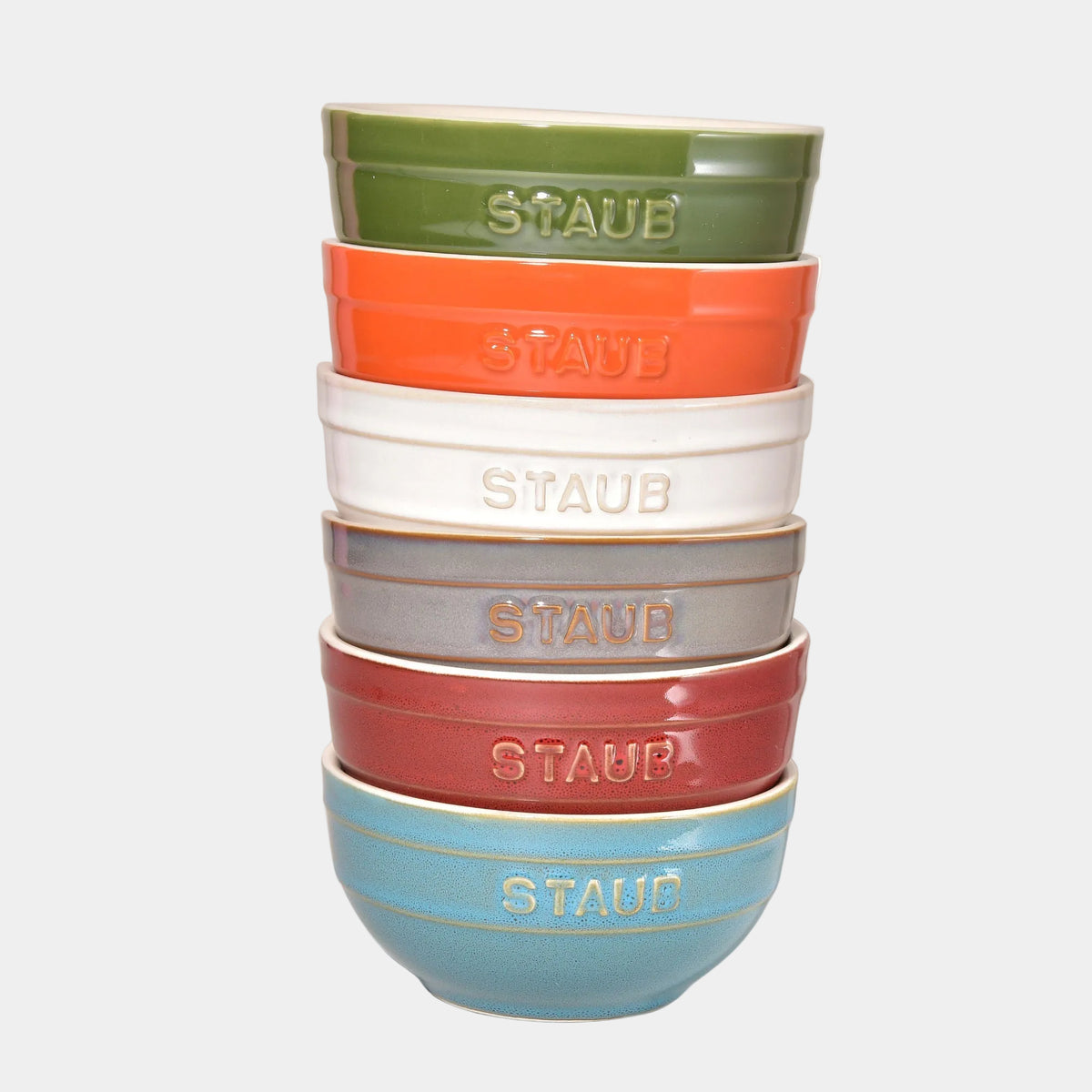 Set of colorful Staub ceramic bowls stacked on a white background