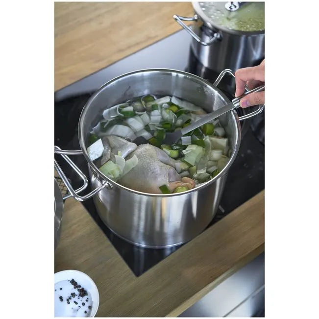 Stainless steel pot on a stove with vegetables and a chicken, being stirred.