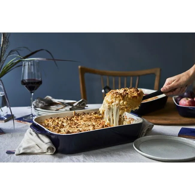 Delicious cheesy dish served from STAUB Ceramique Ceramic Rectangular Oven Dish 1 L, Dark-Blue on a dining table.