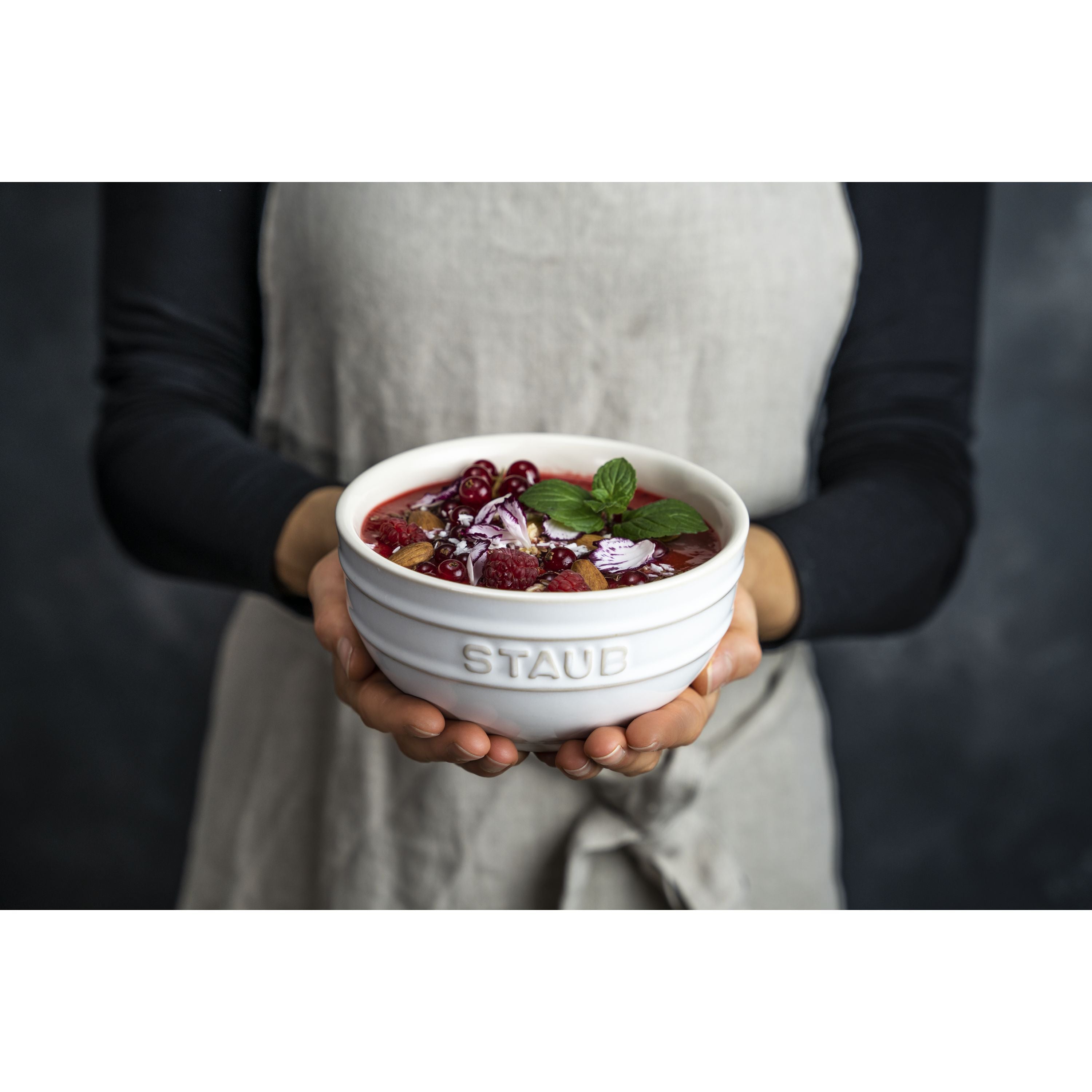 Person holding a filled STAUB Ceramique Ceramic Round Bowl, showcasing its elegant design and versatility.
