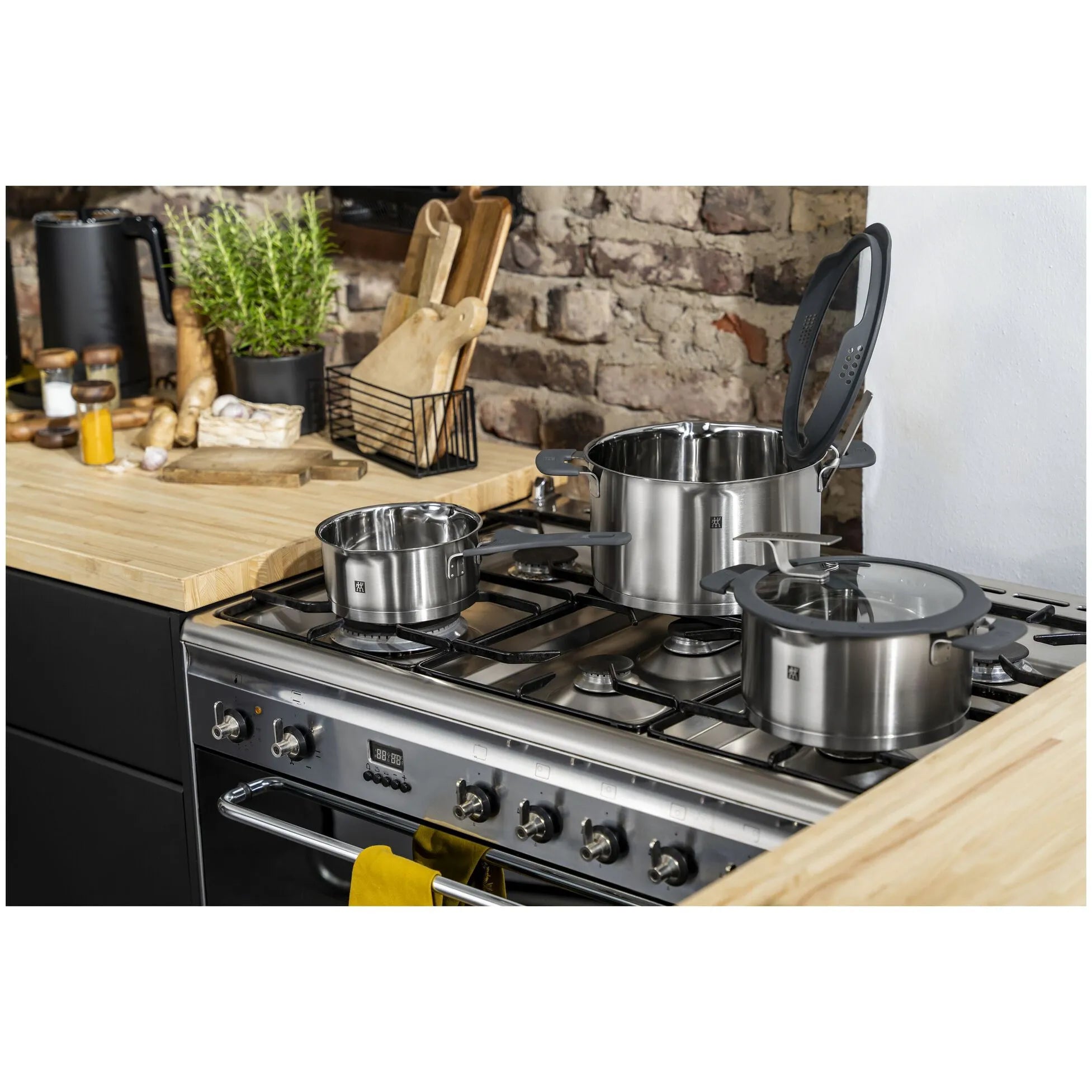 Stainless steel cookware set on a gas stove with a kitchen background