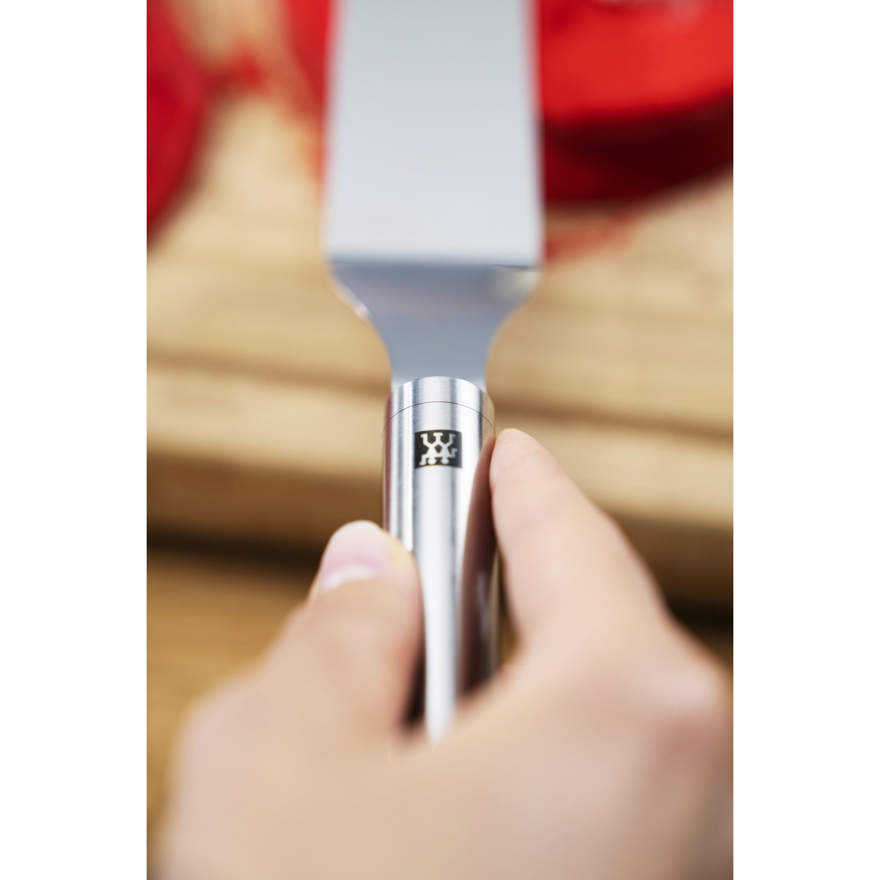 Hand holding ZWILLING Pro Icing Spatula, 18/10 stainless steel handle, perfect for lifting and spreading in baking and cooking.