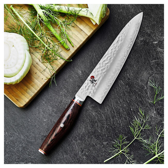 Miyabi 6000 MCT 8 Inch Gyutoh knife on a cutting board with vegetables