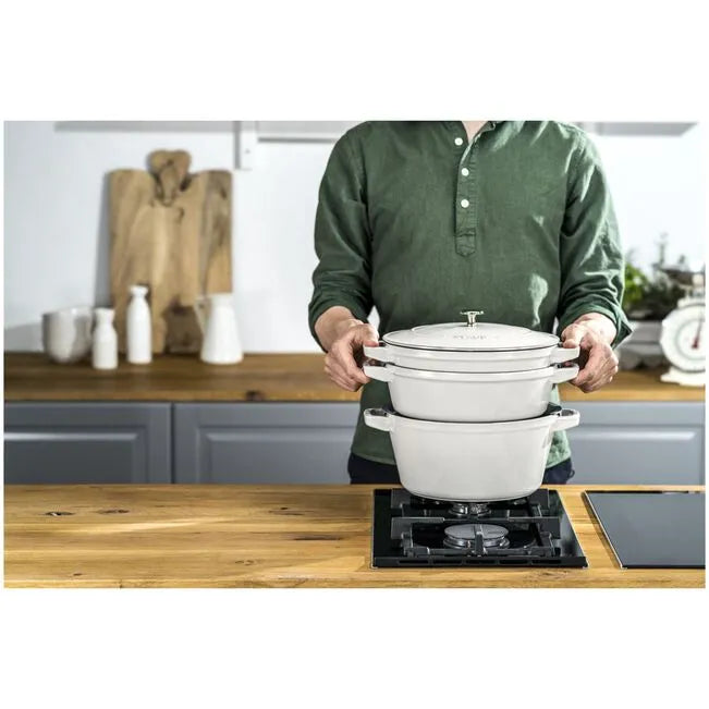 Person holding a stack of white cookware in a kitchen