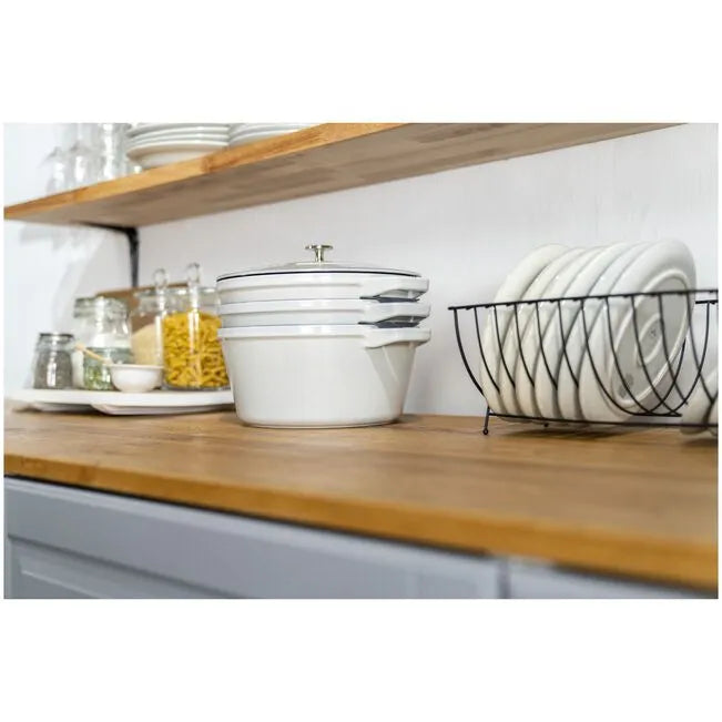 Kitchen counter with cookware set, white bowls, a dish rack, and various kitchen items.