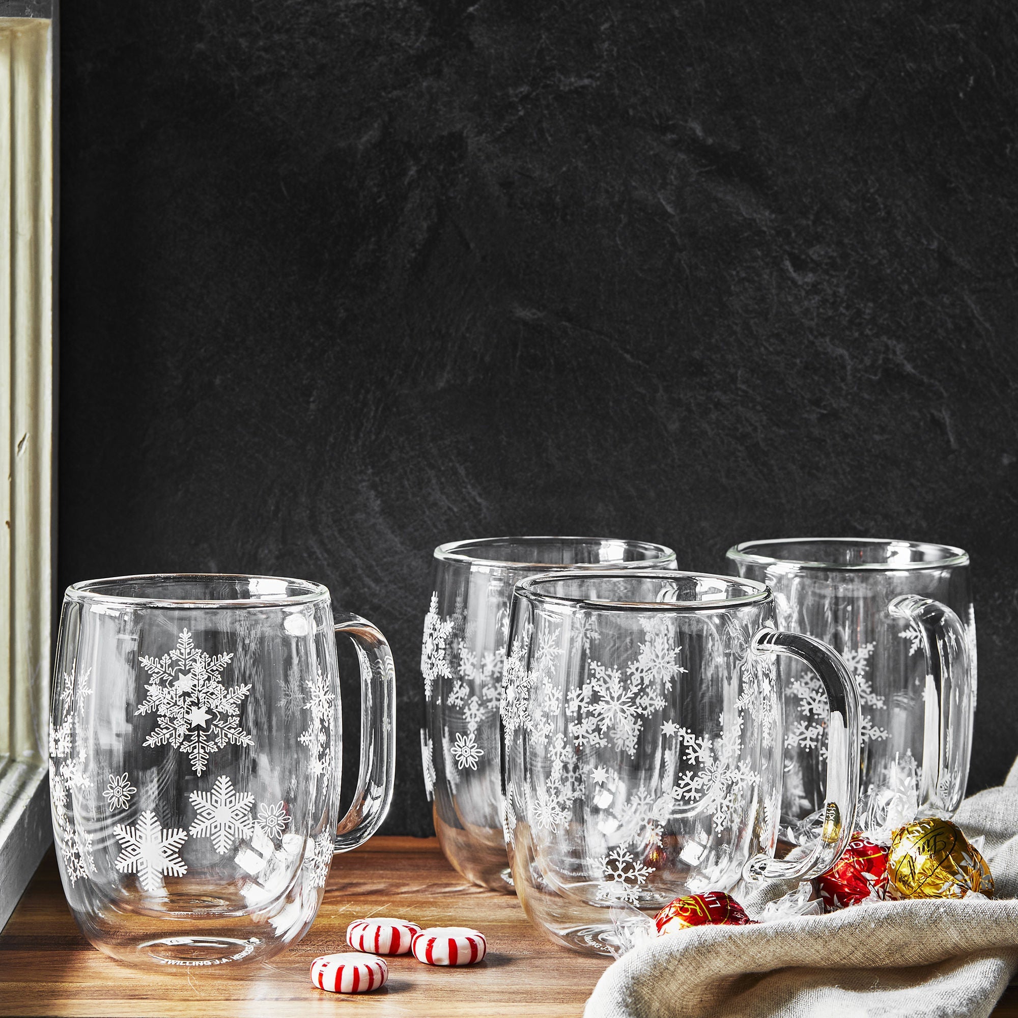 Clear glass ZWILLING Sorrento Plus Snowflake Double-Walled Mug designs on a wooden surface against a dark background