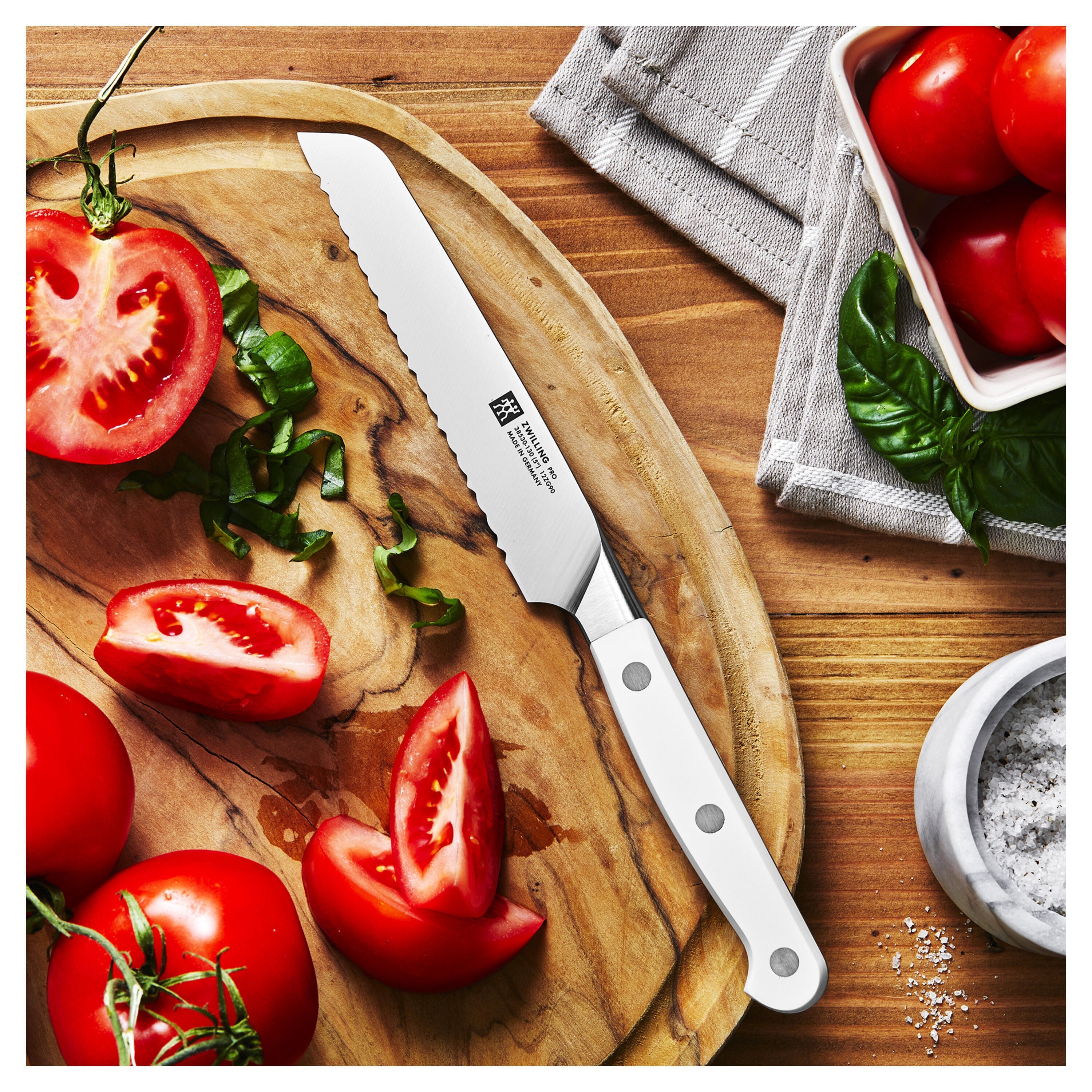 Wooden cutting board with sliced tomatoes and a knife on a wooden surface.