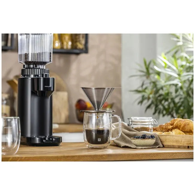 Coffee grinder and brewing setup on a wooden surface with a blurred background