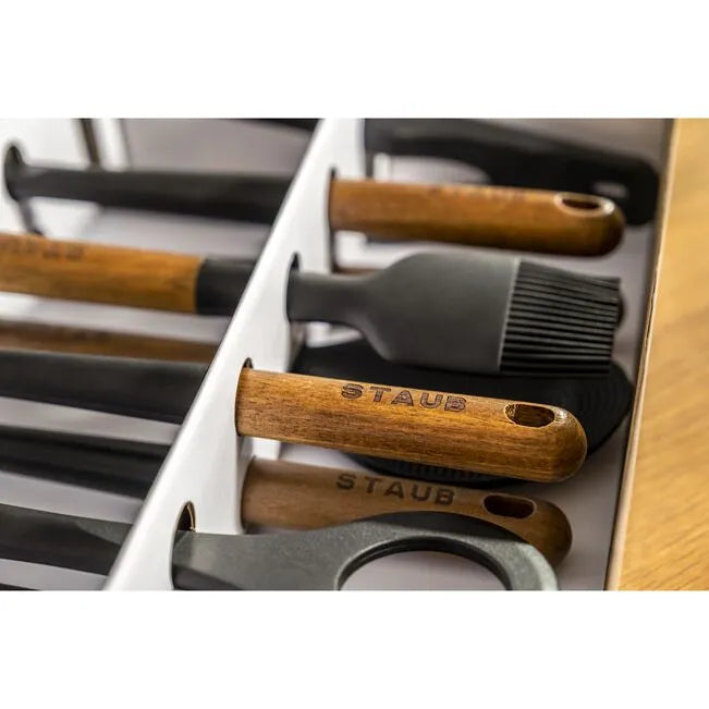 Close-up of Staub Silicone Kitchen Utensil Set showcasing silicone heads and acacia wood handles in box.
