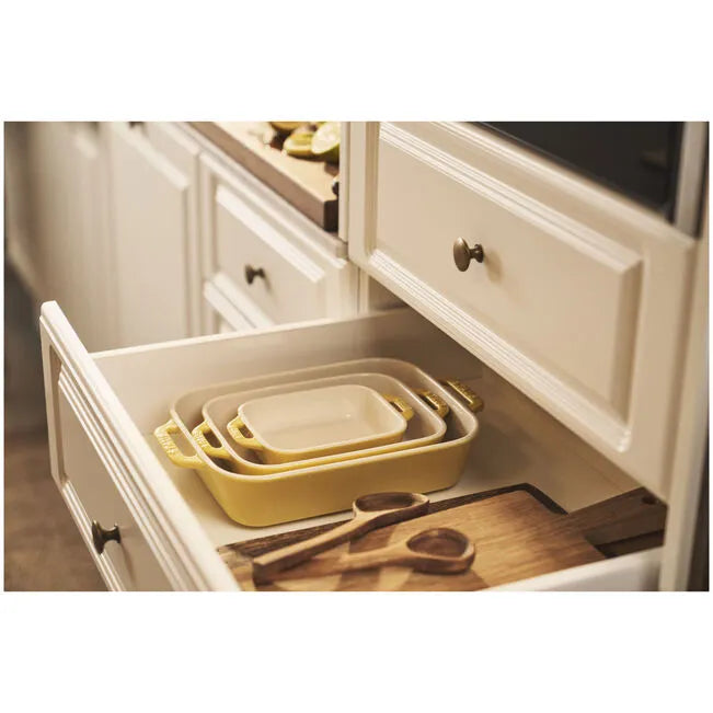 Yellow nesting trays in a kitchen drawer with a cutting board and scissors.