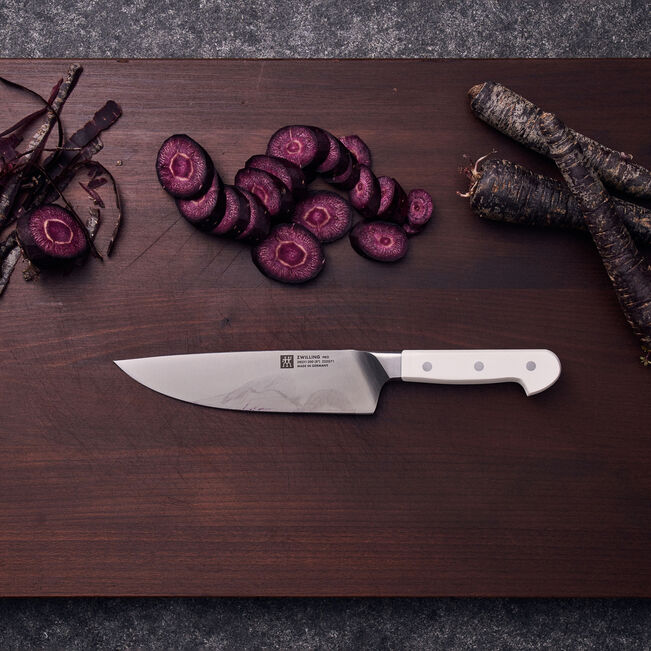 Sliced purple carrots on a wooden cutting board with a knife
