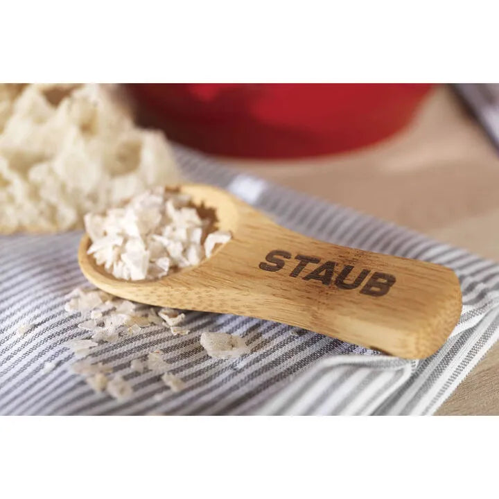 Wooden spoon with 'STAUB' branding with STAUB Ceramique Ceramic Salt Crock on a striped fabric background