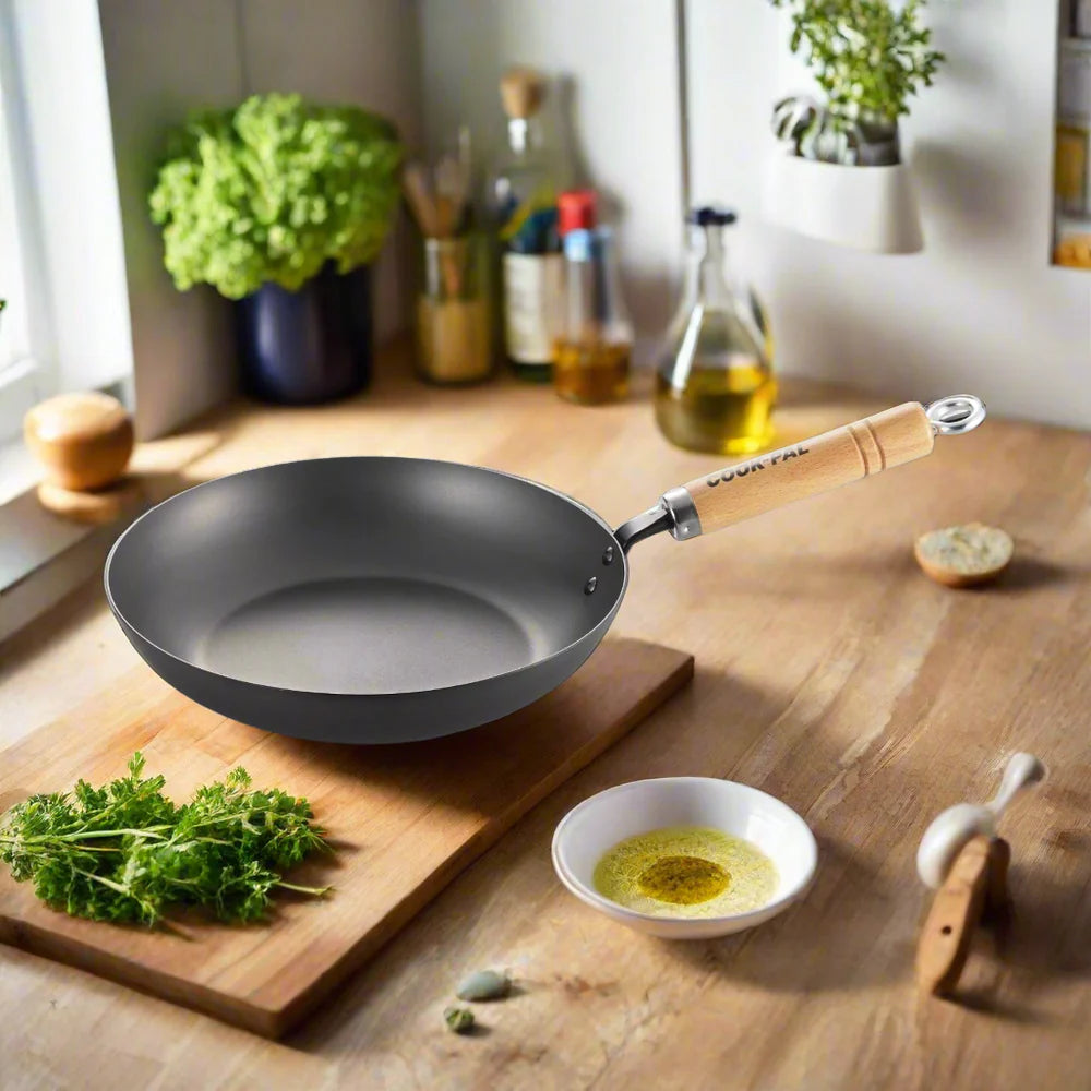 Wok pan with wooden handle on a kitchen counter with ingredients and utensils.