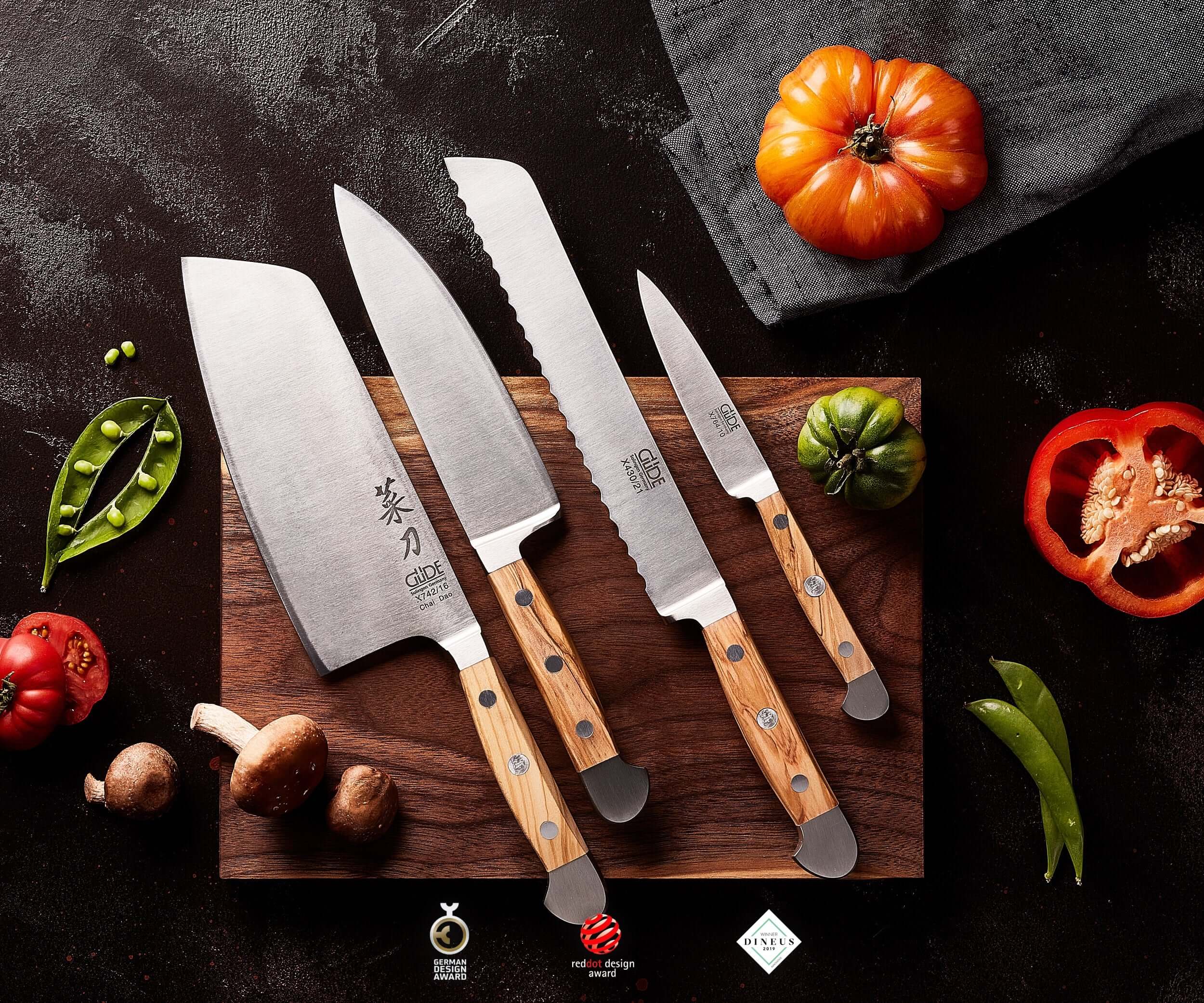 Quatre couteaux GÜDE Solingen sur une planche à découper avec des légumes frais
