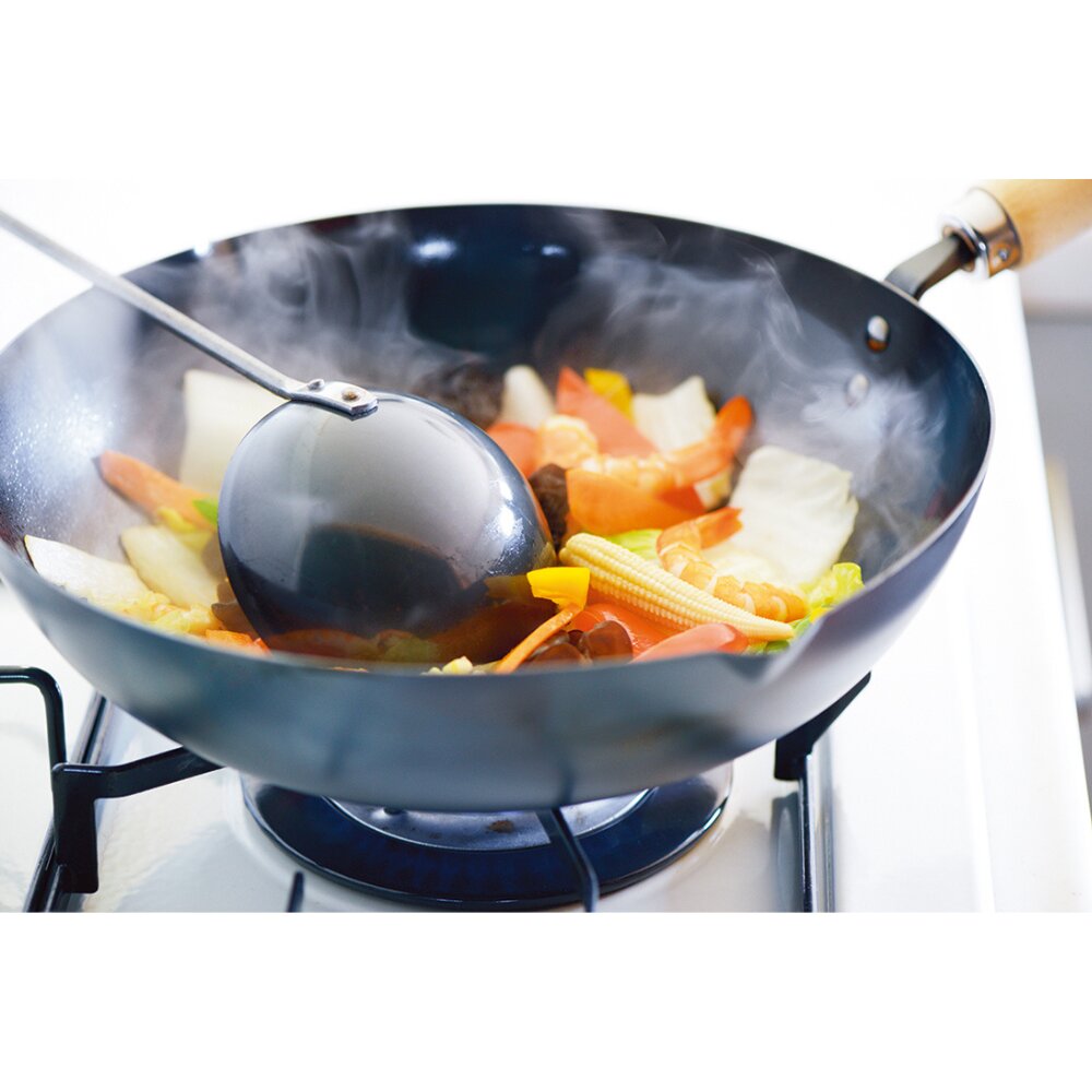Wok with vegetables being cooked on a stove with Yoshikawa Cook-Pal Chinese Ladle 
