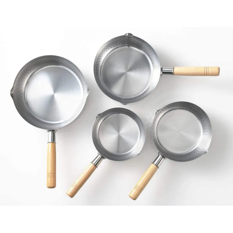 Set of five metallic cookware with wooden handles on a white background