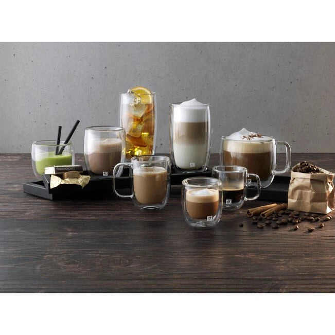 Collection of coffee drinks in various glass mugs on a wooden surface with a gray background.